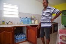 Un homme dans sa cuisine remplie de bouteilles d'eau pour faire face aux coupures d'eau à Capesterre, en Guadeloupe, le 26 juillet 2018