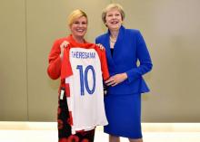 La présidente croate Kolinda Grabar-Kitarovic (g) offre un maillot de la Croatie à la Première ministre britannique Theresa May à l'occasion du sommet de l'Otan, le 11 juillet 2018 à Bruxelles