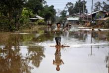 Un homme marche sur une route inondée à Sanamxai, dans la province d'Attapeu, après l'effondrement d'un barrage, le 26 juillet 2018 au Laos