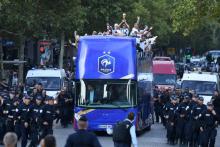 Le défenseur des Bleus Raphaël Varane brandit la Coupe du monde du haut du bus à impériale qui descend les Champs Elysées escorté par les forces de l'ordre, le 16 juillet 2018