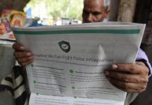 Un vendeur de journaux indien lit un journal avec une annonce de la messagerie WhatsApp déterminée à lutter contre les fake news à New Delhi, le 10 juillet 2018