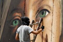 Jorit Agoch, artiste italien, peint sur le mur de séparation israélien en Cisjordanie occupée un portrait géant de l'adolescente Ahed Tamimi, le 25 juillet 2018
