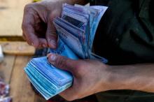 Un homme compte des billets de 1000 bolivars au marché municipal de Coche, près de Caracas, le 20 juin 2018 au Venezuela