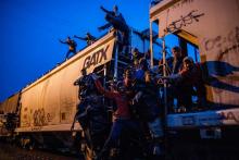 Des migrants illégaux agrippés à un train de marchandises en direction des Etats-Unis, traversent de nuit le village de Las Patronas, le 9 août 2018 dans l'Etat du Veracruz, au Mexique