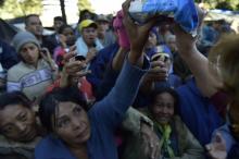 Des Vénézuéliens, installés dans un campement de fortune près d'une gare de bus, reçoivent un peu de nourriture, le 9 août 2018 à Quito, en Equateur