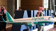 Photo de Saoudiens passant devant une réplique d'un avion de la compagnie saoudienne Flynas, prise le 16 janvier 2017 à Ryad