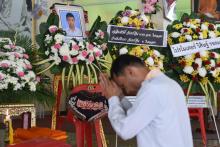 Un homme en prières devant un portrait du jeune boxeur thaïlandais Anucha Tasako mort durant un combat, lors de ses funérailles dans un temple bouddhiste de la province de Samut Prakan le 14 novembre 