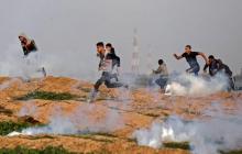 Des manifestants palestiniens fuient les gaz lacrymogènes tirés par des soldats israéliens postés à la barrière de sécurité séparant la bande de Gaza, une enclave palestinienne, du territoire israélie