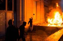 Un homme jette une pierre près d'un véhicule en feu lors d'une manifestation des "gilets jaunes" contre la politique du gouvernement à Paris, le 1er décembre 2018