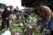 Des vendeurs tentent de sauver leurs légumes après l'explosion d'une voiture piegée près d'un marché de la ville d'Afrine, dans le nord de la Syrie qui a fait au moins neuf morts le 16 décembre 2018