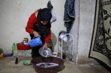 Cédra al-Hassan, une déplacée syrienne de Deir Ezzor, fait la vaisselle dans une bassine posée à même le sol dans une cave de la ville d'Al-Bab (nord de la Syrie), où elle habite aux côtés d'une dizai