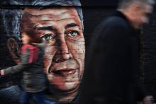 Des passants marchent à Belgrade le 14 janvier 2019 devant une fresque murale avec le portrait d'Oliver Ivanovic, homme politique serbe du Kosovo assassiné l'année précédente