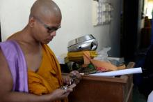 Un moine bouddhiste près d'un bol d'aumônes (centre) troué par les balles des assaillants qui ont tué deux moines et en ont blessé deux autres au temple de Rattanaupap dans le sud de la Thaïlande, le 