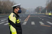 Un policier chinois porte un masque pour se protéger de la pollution dans une avenue de Pékin, le 13 mars 2018