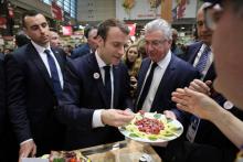 Le président Emmanuel Macron (C) goûte de la viande crue sur le stand des "flexitariens" au salon de l'Agriculture, le 23 février 2019 à Paris