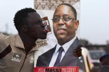 Un homme fait une grimace devant une affiche électorale du président sénégalais sortant Macky Sall le 7 février 2019