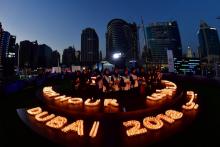Des participants à la Earth Hour tiennent des bougies devant les immeubles de Dubaï éteints, le 24 mars 2018