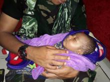 Un soldat indonésien tient dans ses bras un bébé rescapé des inondations qui ont frappé la province indonésienne de Papouasie le 17 mars 2019