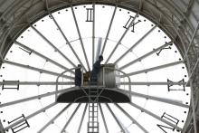 Un employé change l'heure d'une horloge géante à Cergy en prévision du passage à l'heure d'été le 26