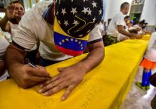 Un migrant vénézuélien à Curaçao signe un drapeau pendant une manifestation de soutien à l'opposant Juan Guaido, le 22 février 2019