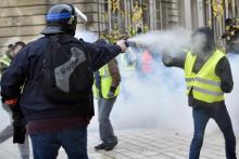 Un policier envoie du gaz lacrymogène à un manifestant Gilet jaune