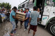 Josué Angulo (c avec la casquette) transporte avec un ami un groupe électrogène qu'il vient d'acheter à Cucuta ville frontière entre la Colombie et le Venezuela, le 10 avril 2019