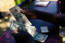 Un agent de sécurité compte de petites coupures de dollar le 13 mars 2019 à Mutoko, au Zimbabwe
