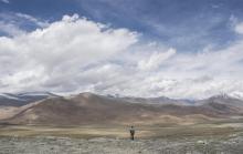 Photo archive montrant un homme regardant une portion de la route de l'amitié entre la Chine et le Pakistan (à droite) et la montagne Karakorum près de Tashkurgan dans la province chnoise du Xinjiang,