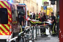 Des pompiers évacuent une personne blessée dans l'explosion d'un colis piégée dans une rue piétonne de Lyon, le 24 mai 2019