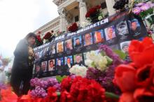 Une femme dépose des fleurs le 2 mai 2019 à Odessa devant les portraits de militants prorusses tués il y a cinq ans lors d'un incendie