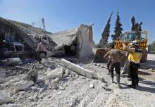 Des secouristes en zones rebelles, les Casques blancs devant un de leurs bâtiment détruit dans un bombardement, selon l'Observatoire syrien des droits de l'Homme, le 13 mai 2019