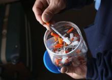 Un toxicomane choisit une seringue pour s'injecter de l'héroïne, le 23 mars 2016 à New London, aux E