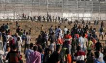 Des manifestants palestiniens tentent de monter sur la clôture entre la bande de Gaza et Israël lors d'affrontements à l'est de Gaza le 3 mai 2019