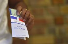 Une femme tient en main sa carte d'électeur et sa pièce d'identité lors des élections législatives à