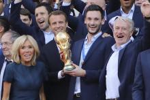Le président Emmanuel Macron avec le capitaine des Bleus Hugo Lloris brandissent le trophée de champions du monde à l'Elysée, lors d'une réception le 16 juillet 2018