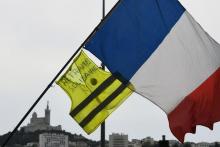 Un manifestant brandit un gilet jaune et un drapeau de la France lors d'une manifestation à Marseille, le 20 avril 2019