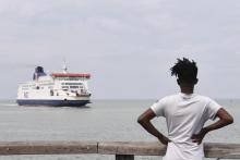 Un migrant regarde l'arrivée d'un ferry dans le port de Calais, le 12 août 2019