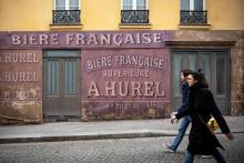 Deux personnes passent dans une rue où a été installé un décor de cinéma dans le quartier de Montmartre, le 21 mars 2020 à Paris