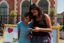 Deux adolescentes regardent sur un smartphone l'application "Je ne suis pas seule" permettant aux fe