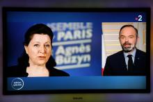 Une photo d'Agnès Buzyn est affichée sur l'écran de la télévision alors que le Premier ministre Edouard Philippe s'exprime le 17 mars 2020 sur France 2