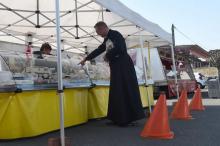 Un prêtre achète du fromage sur le marché de Illiers-Combray, dans le centre de la France, avec des plots pour délimiter les distances de sécurité entre les clients, le 20 mars 2020
