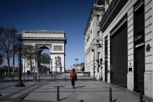 Une personne marche avenue des Champs-Elysées, déserte, pendant le confinement instauré pour lutter contre l'épidémie du nouveau coronavirus, le 23 mars 2020 à Paris
