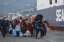 Des migrants s'apprêtent à embarquer du port de Mytilène (île de Lesbos) vers le nord de la Grèce, le 20 mars 2020
