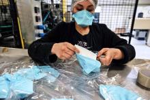 Une employée emballe des masques de protection resppiratoire sur une ligne d'assemblage de l'usine Valmy, le 28 février 2020 à Mably, dans la Loire