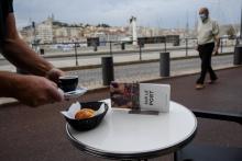 Un homme portant un masque de protection passe à côté de la terrasse d'un café sur le Vieux Port, le 2 juin 2020 à Marseille