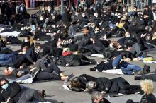 Des manifestants vêtus de noir gisent sur le sol pour représenter la "mort" de leur entreprise lors d'une manifestation réclamant la réouverture des commerces "non essentiels" à Perpignan, le 16 novem