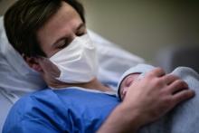 Un père portant un masque tient son bébé contre sa poitrine durant la deuxième vague de Covid-19 à la maternité des Diaconesses à Paris, le 17 novembre 2020