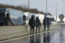Des migrants marchent sur l’autoroute A16, près de Calais, tentant de monter dans des camions en route vers l’Angleterre, le 17 décembre 2020