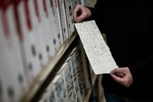 Une employée des archives municipales de Dijon montre le 20 janvier 2021 un texte manuscrit de 1856 trouvé dans le mur d'une chapelle