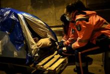 Des bénévoles de la protection civile s'adressent à un sans-abri installé dans une tente à Paris, le 9 février 2021 nuit de grand froid